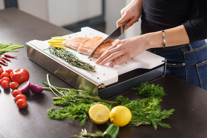 Schneidebrett mit Auffangschale in Kunststoff auf dem Lachs und Kräuter geschnitten werden