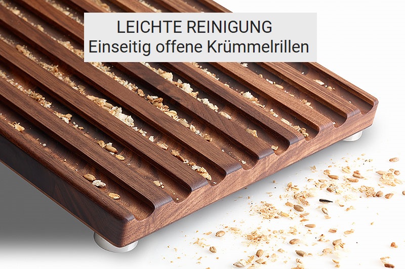 Offene Krümmelrillen in Brotschneidebrett Nussbaum aus denen Brotkrümmel herausfallen